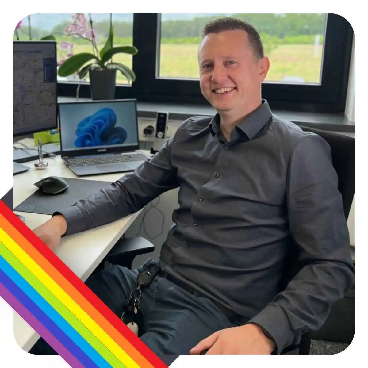 Disponent Dimitri Schmied lächelt in die Kamera am Arbeitsplatz sitzend.